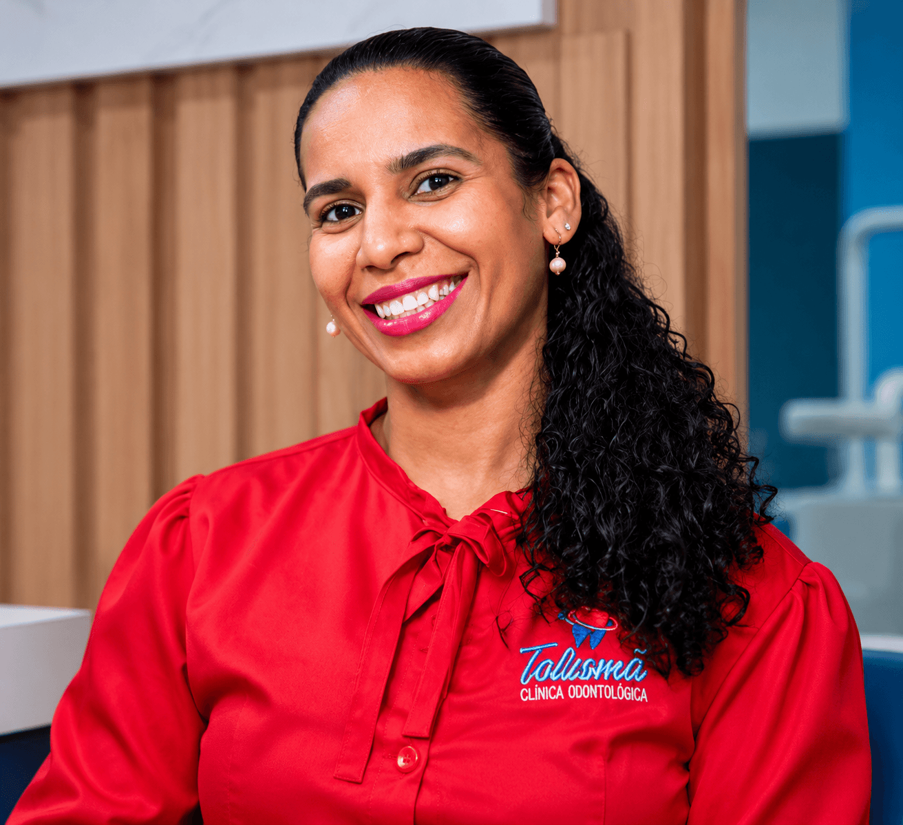 Profissional da Talismã sorrindo, com camisa vermelha bordada com a logo da clínica